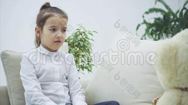 可爱的<strong>小女孩</strong>坐在沙发上，和她的泰迪<strong>说话</strong>。 它不了解她。 她看起来很失望。