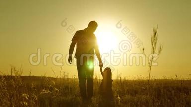 小女儿和爸爸牵着手在田野里<strong>走来走去</strong>。 孩子握着父亲`手。 一家人晚<strong>上</strong>步行出城