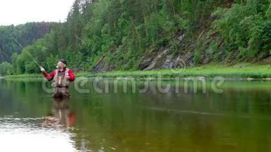 在山上的<strong>河边钓鱼</strong>。 一个穿着红色衣服，头上戴着绷带的老人扔苍蝇渔具。 运动或h