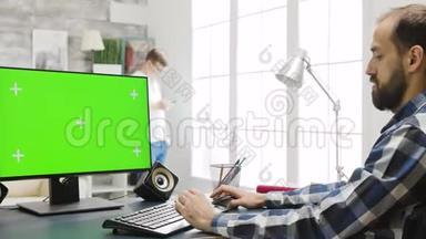 在舒适明亮的客厅里使用绿色屏幕的个人电脑显示器
