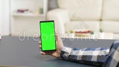 放大桌上拿着绿色屏幕手机的人的视差镜头