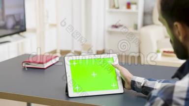 一个人滚动触摸一个绿色屏幕的数字平板电脑