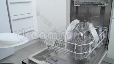 一个女人把脏盘子和盘子放进<strong>洗碗机</strong>里。