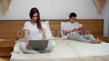 两个女孩和男人在<strong>床上</strong>使用笔记本电脑和电话。 <strong>坐在床上</strong>的年轻女子