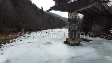 一条半冻的河流过一座破旧的桥塔
