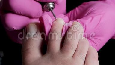 带粉色手套的教育学大师是用钻头在修脚沙龙切割角质层和紫胶脚趾甲。 专业教育