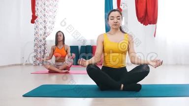瑜伽-两个冷静的女人坐在<strong>垫子</strong>上做呼吸练习