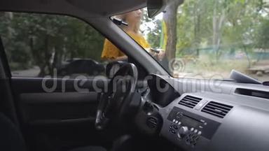 一个女人从挡风玻璃上的雨刷下面抽出一张违章<strong>停</strong>车罚单，坐在车里。