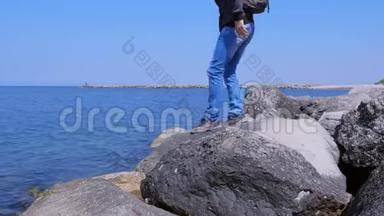 旅人来海边坐大石头欣赏海景度假。