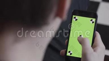 男士双手使用带有绿色<strong>屏幕</strong>的移动智能手机，侧肩观看。 库存录像。 接近人类<strong>滚动</strong>