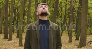 一个白发苍苍的白人男子的特写镜头站在森林里抬头看。 穿着休闲服装的男人，享受着宁静