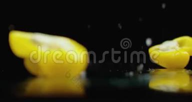 一个黄色的切钟胡椒落在玻璃上，水在黑暗的背景上缓慢地飞溅。