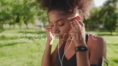 一位非洲裔美国年轻健身妇女在公园<strong>跑步</strong>前，在耳朵里<strong>呼吸</strong>并插入耳机