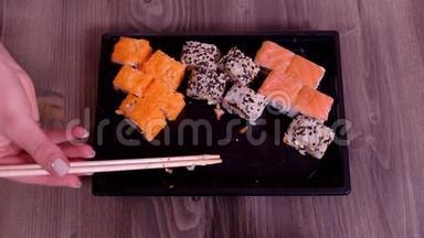 用筷子吃寿司。 手拿筷子吃寿司..