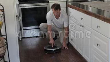 成年男子正在厨房地板上放置圆形机器人吸尘器，<strong>切换</strong>