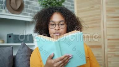 漂亮的非裔美国女人在家看书，<strong>翻页</strong>微笑