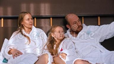 一个幸福的家庭，穿着<strong>白色浴袍</strong>坐在床上互相交谈