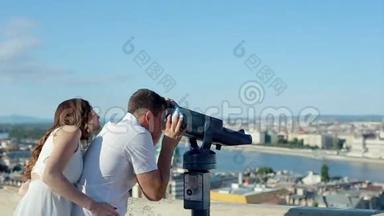 男青年带着女人在观景点用Coin操作的双眼看城市之美
