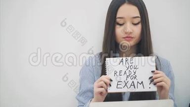 可爱的亚洲小姐坐着，拿着笔记本电脑，拿着一张纸`你准备好考试了吗？