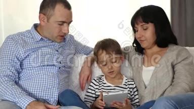 孩子玩平板电脑。 父亲和母亲和儿子一起在平板电脑上看电影。 这就是