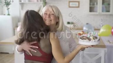 女儿祝妈妈生日快乐，给她巧克力蛋糕。 女人拥抱和微笑。 生日庆典