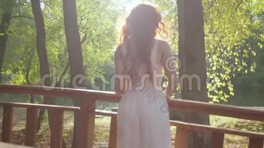 后景<strong>美丽</strong>苗条的女人，红色的头发，穿着白色的长裙，站在桥上看着远处。 <strong>美丽美丽</strong>