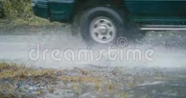 汽车轮胎在农村公路上的一个泥泞的泥坑里滚动和飞溅，动作缓慢
