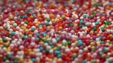 五颜六色的糖糖落在桌子上。 多种颜色的悬垂物落入五颜六色的球中。 红蓝绿色