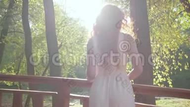 后景红发白种人女子穿着浅白色连衣裙站在秋天公园的阳光下。 年轻女孩<strong>花钱</strong>