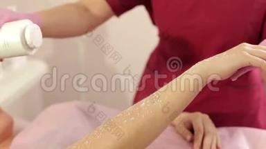 美容师在脱毛前`一个年轻女孩的手上撒上滑石粉。
