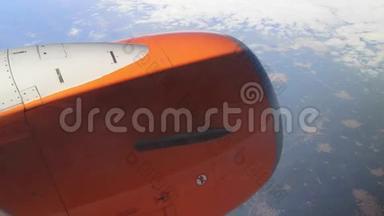 一架橙色的飞机飞越卷曲的云层，通过这些云层可以看到景观21。 一架蓝色飞机的明亮涡轮