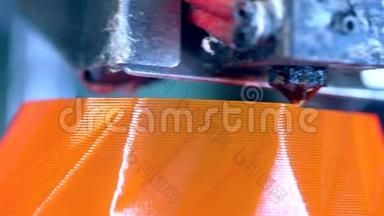 一个3D打印机的头部正在创造薄薄的橙色层。 3D打印机在3D打印实验室工作。