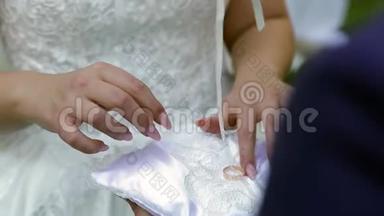 新郎把结婚戒指从<strong>垫子</strong>上拿出来放在新娘`手指上