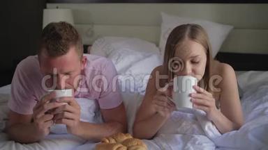 一对在床上享受早咖啡的夫妇