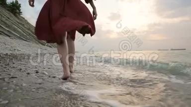 近景后景的双腿白种人女孩<strong>走</strong>在海边的石头海岸的<strong>水中</strong>，<strong>走</strong>向夕阳。