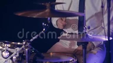 穿着白色衬衫和黑色领带的鼓手在充满蓝色的舞台上打鼓