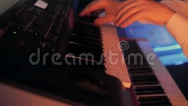 钢琴家的特写`他的手在<strong>蓝色</strong>灯光的<strong>舞台</strong>上用键盘弹奏一首歌