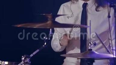 穿着白色衬衫和黑色领带的鼓手在充满蓝色的舞台上<strong>打鼓</strong>