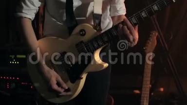 穿着白色衬衫和黑色领带的吉他手<strong>轻轻地</strong>用白色吉他弹奏和弦