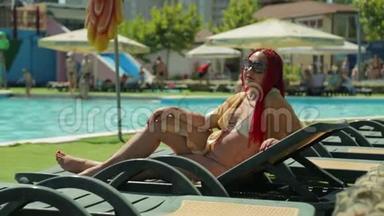 一个红头发的女人在游泳池旁的日光浴室里晒太阳