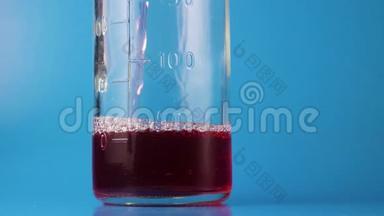 粉红色液体的电影胶片倒入深蓝色背景的玻璃量瓶中