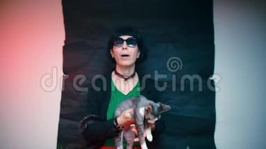 一个穿着深色衣服的女人<strong>抚摸</strong>着一只德文克斯猫在她怀里。