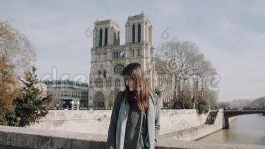 快乐优雅美丽的女人摆在令人惊叹的巴黎圣母院大教堂附近，享受晴朗的晴天慢动作。