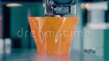 3D打印机正在生产一个橙色花瓶。在3d打印实验室工作的3d打印机。