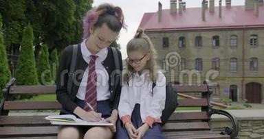 两个坐在长凳上的女学生，小学生和<strong>高中</strong>生。