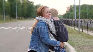 快乐的妈妈在<strong>放学</strong>前拥抱她的小儿子，他们站在路上拥抱。