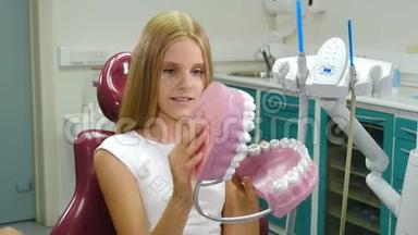 儿童牙科学。<strong>牙齿保护</strong>理念。漂亮的10岁女孩手里拿着<strong>牙齿</strong>模型。微笑开朗的病人