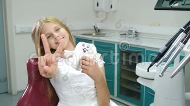 在牙医办公室<strong>微</strong>笑的孩子。 小病人看着相机<strong>微</strong>笑。 拇指向上。 可爱的少女