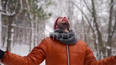 在圣诞节假期的<strong>寒假</strong>里，在户外享受降雪的嬉皮士男子。 快乐的家伙在雪地里张开双臂