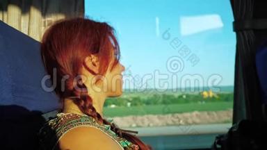 一个孤独的红发旅行女孩<strong>看着</strong>公共汽车<strong>窗外</strong>的道路运输，自然和蓝天。